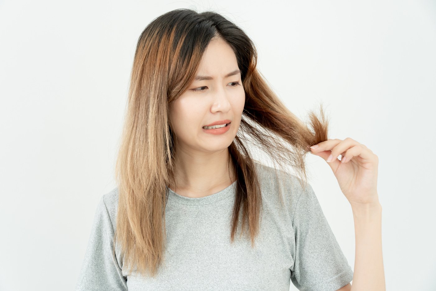 Asian woman very sad and upset looking at damaged hair, hair los